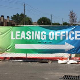 A large banner guides guests to the leasing office of an apartment complex
